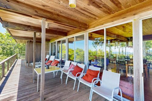 a porch with white chairs and a table and windows at The Eliot Noyes in Chilmark
