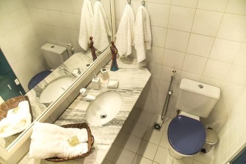 a bathroom with a sink and a toilet and a mirror at Apt. Enseada Praia do Forte in Praia do Forte