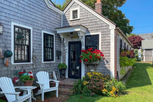 a house with two chairs and a table and flowers at The Groggy Anchor in Provincetown