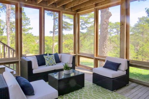 a screened in porch with white furniture and windows at Blackfish Bungalow in Wellfleet