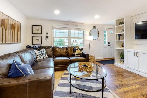 a living room with a leather couch and a glass table at Harbortown Hideaway in Falmouth