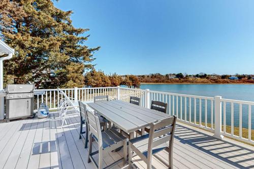 a wooden table and chairs on a deck next to the water at Island Bay Bungalow in Eastham