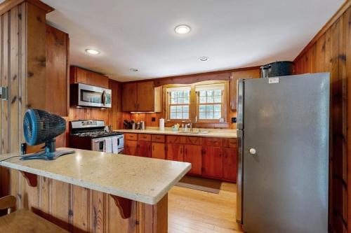 a kitchen with wooden cabinets and a stainless steel refrigerator at Pickerel Cove Cottage in Mashpee