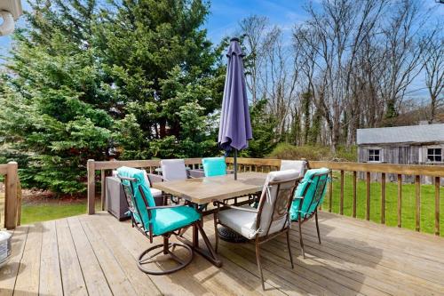 a table with chairs and an umbrella on a deck at Namskaket Retreat in Orleans