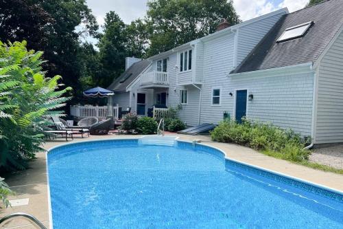 a swimming pool in front of a house at Moon Compass Manor in Sandwich