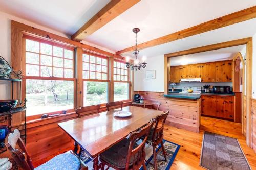 a dining room with a wooden table and some windows at Pretty on Prada in Edgartown