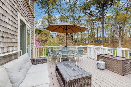 a patio with a table with an umbrella and chairs at Cozy Charming Cottage in Brewster