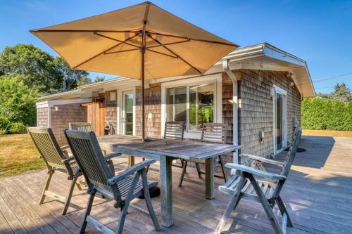 a wooden table and chairs with an umbrella on a deck at Yellow Brick Road House in Oak Bluffs