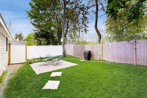 a backyard with a fence and a table and chairs at The Quintessential Cape Cottage in Orleans