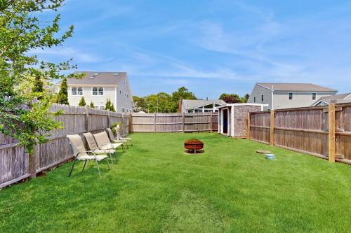 a backyard with a fence and chairs on the grass at Salty Kisses Unit 20 in Yarmouth