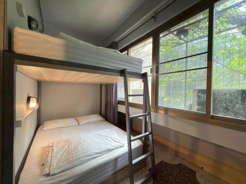 a bedroom with two bunk beds and a window at Merge Hostel Chinatown in Samphanthawong