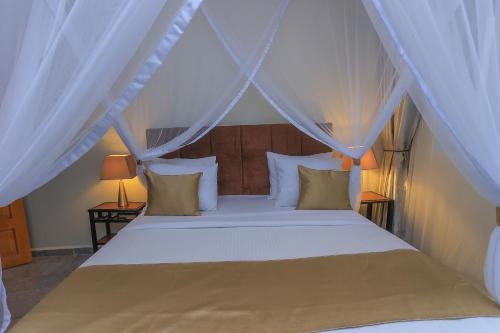 a bedroom with a white bed with a canopy at Bon Bini Residence Apart-Hotel - Pool, Fast WiFi, Security, Backup Power in Kampala