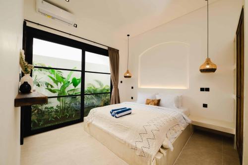 a bedroom with a bed and a large window at Rumah Mana Villa in Tabanan