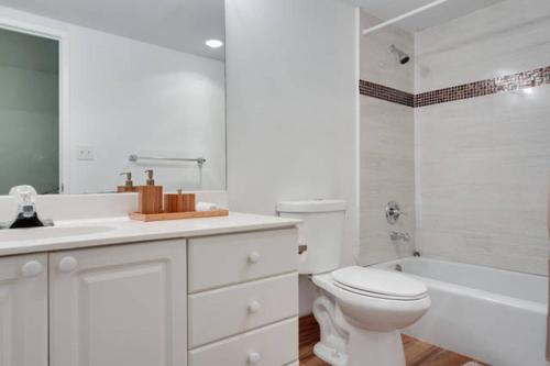 a white bathroom with a toilet and a bath tub at Sunny Isles Ocean Reserve Condo Apartments in Miami Beach