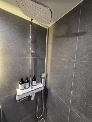 a shower with three bottles on a shelf in a bathroom at LUVO Signature Hotel in Seoul