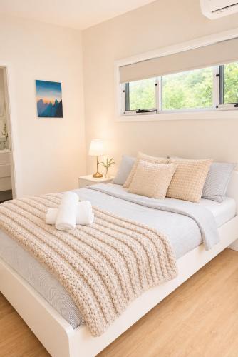 a white bedroom with a large bed with pillows at Cosy Granny flat in Epping in Epping