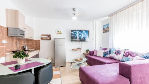 a living room with a purple couch and a kitchen at Lake Side Apartments by ZagrebRent in Zagreb