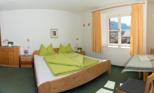 een slaapkamer met een bed met groene kussens en een raam bij Krebishof Agriturismo in Schenna