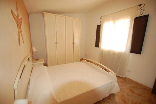 a bedroom with a white bed and a window at Tenute Costadoria (Valle di Cynara) in Valledoria