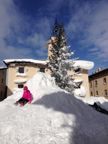 a child sitting in a pile of snow in front of a building at Il Peschio in Pescocostanzo