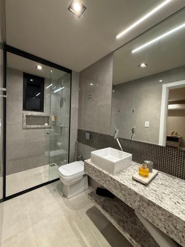 a bathroom with a toilet and a sink and a shower at Suíte Boutique 302 Cheia de Graça in Divinópolis