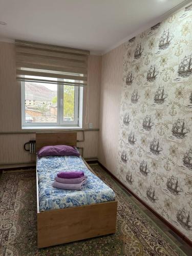 a small bedroom with a bed with a window at Arzu Guesthouse in Ak-Say