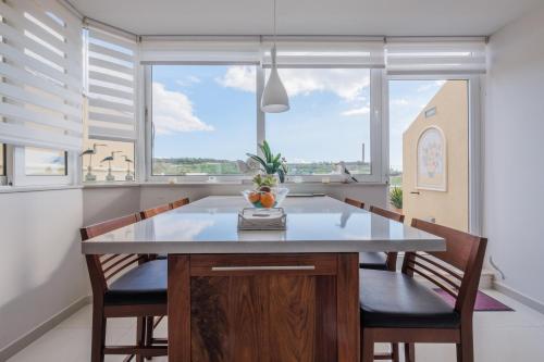 eine Küche mit einem Tisch und Stühlen sowie einem großen Fenster in der Unterkunft Seagull Penthouse Marsaxlokk in Marsaxlokk