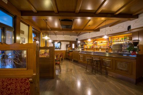 a bar in a restaurant with a counter and chairs at Hotel Al Cervo in Tesero