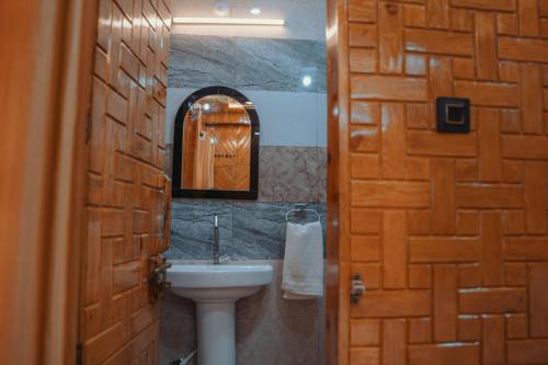 a bathroom with a sink and a wooden door at Jigyasa Homestay in Almora