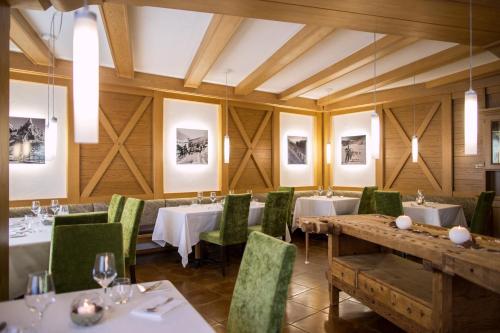 een eetkamer met tafels en groene stoelen bij Hotel Al Cervo in Tesero