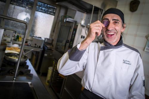 a chef talking on a cell phone in a kitchen at Hotel Al Cervo in Tesero