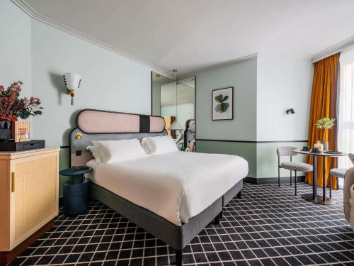 a hotel room with a large bed and a table at Hotel Faubourg Galant Paris - Handwritten Collection in Paris
