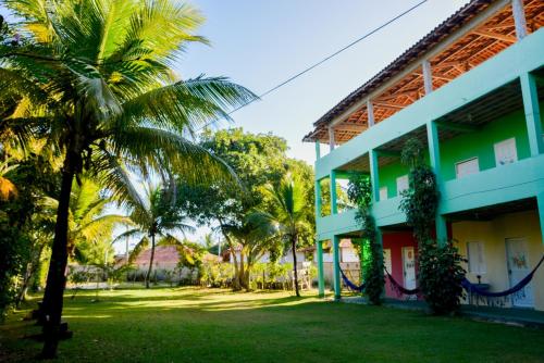 a palm tree next to a building with a yard at Pousada Sol Nascente in Cumuruxatiba