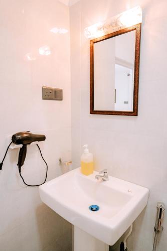a bathroom with a white sink and a mirror at Elee Villa - Waterfront Retreat with Victoria Reservoir & Mountain Views in Teldeniya