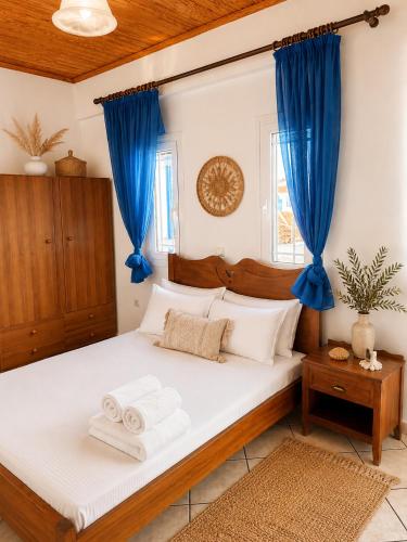 a bedroom with a large bed with blue curtains at Meltemi Apartments in Elafonisos