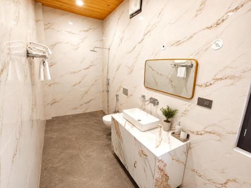 a white bathroom with a sink and a mirror at Corbett Retreat in Rāmnagar