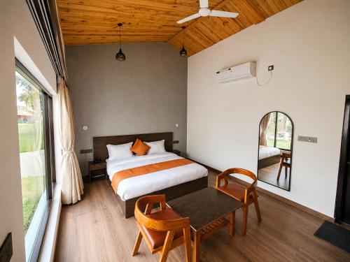 a bedroom with a bed and a table with chairs at Corbett Retreat in Rāmnagar