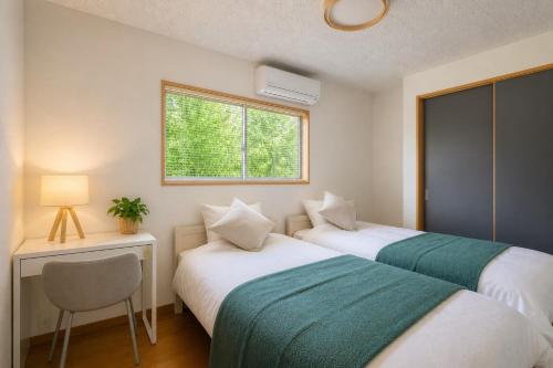 two beds in a room with a desk and a window at Building D - Vacation STAY 84939v in Bōchū