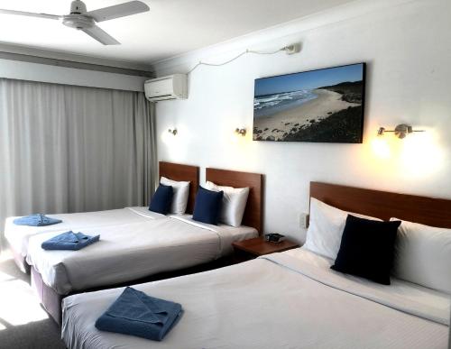 a hotel room with two beds and a beach at Port O'Call Motel in Port Macquarie