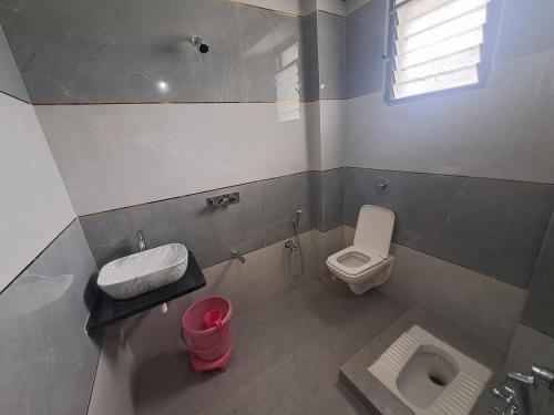 a small bathroom with a toilet and a sink at Hotel Sai Neelam in Shirdi