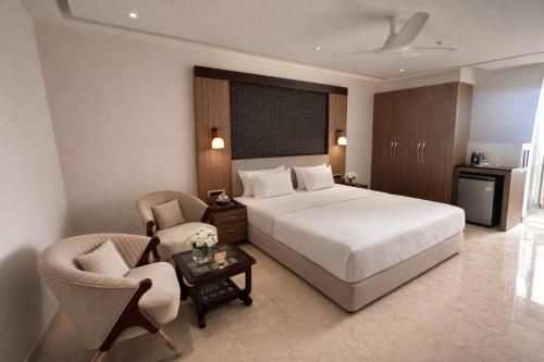 a hotel room with a bed and two chairs at Hotel Hider in Gurgaon