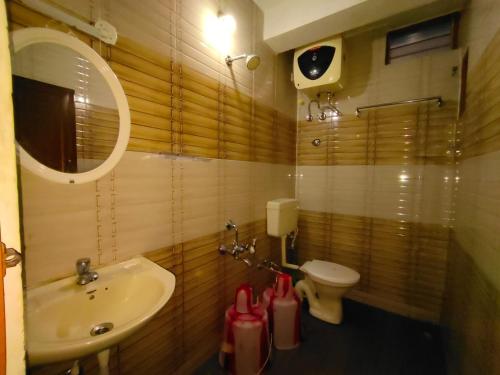 a bathroom with a sink and a toilet and a mirror at Kodai Mistview Cottage in Kodaikānāl