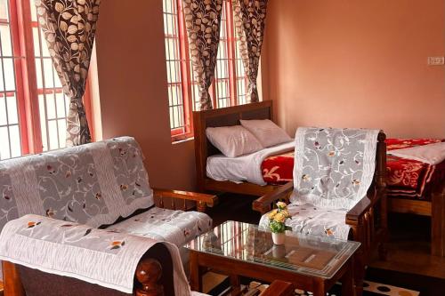 a room with a bed and two chairs and a table at Kodai Mistview Cottage in Kodaikānāl