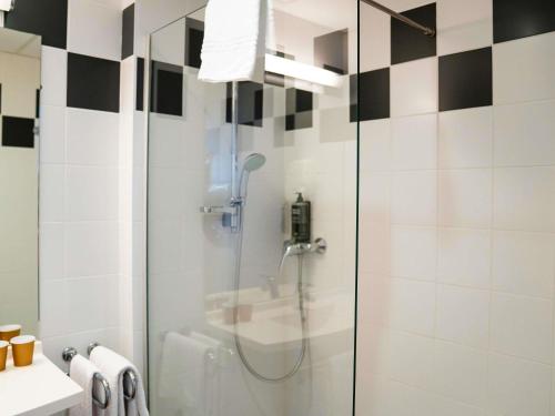 a shower with a glass door in a bathroom at ibis Styles Bourbon Lancy in Bourbon-Lancy