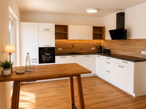 a kitchen with white cabinets and a wooden table at Schongau Suites Premium Apartments M in Schongau