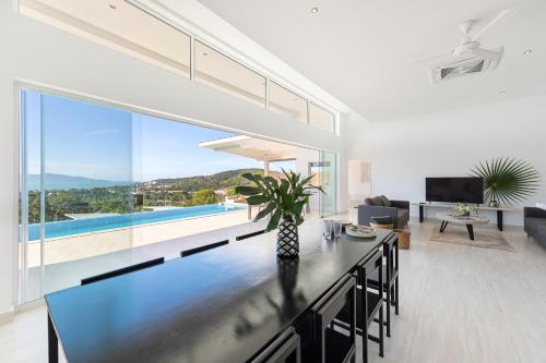 a living room with a dining table and large windows at Rockstarvillas Grande Siesta in Nathon Bay