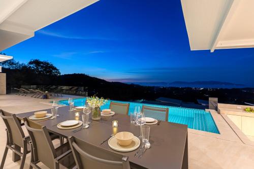 a dining table with a view of a pool at Rockstarvillas Grande Siesta in Nathon Bay