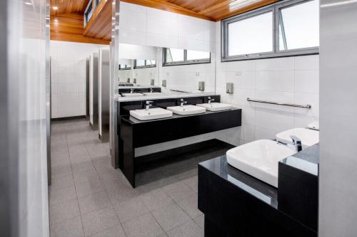 a bathroom with three sinks and two mirrors at BIG4 Emu Beach Holiday Park in Albany