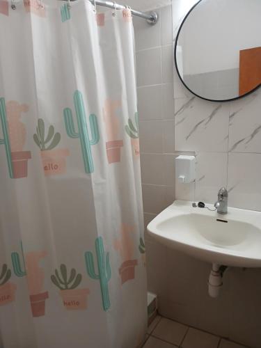 a bathroom with a sink and a shower curtain with cactus at Doukas in Skala Rachoniou