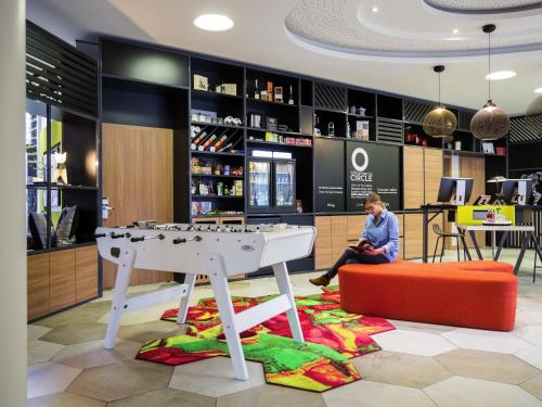 a woman sitting on a stool in a store with a table at Aparthotel Adagio Köln City in Cologne